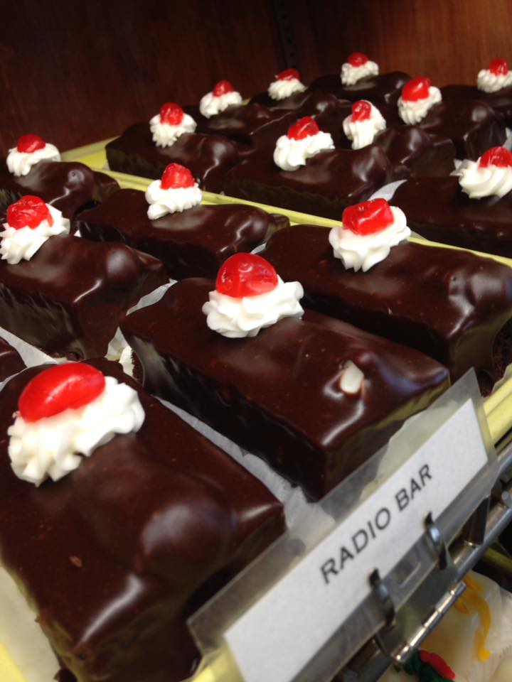 A bakery case tray of Radio Bars topped with cream and cherries